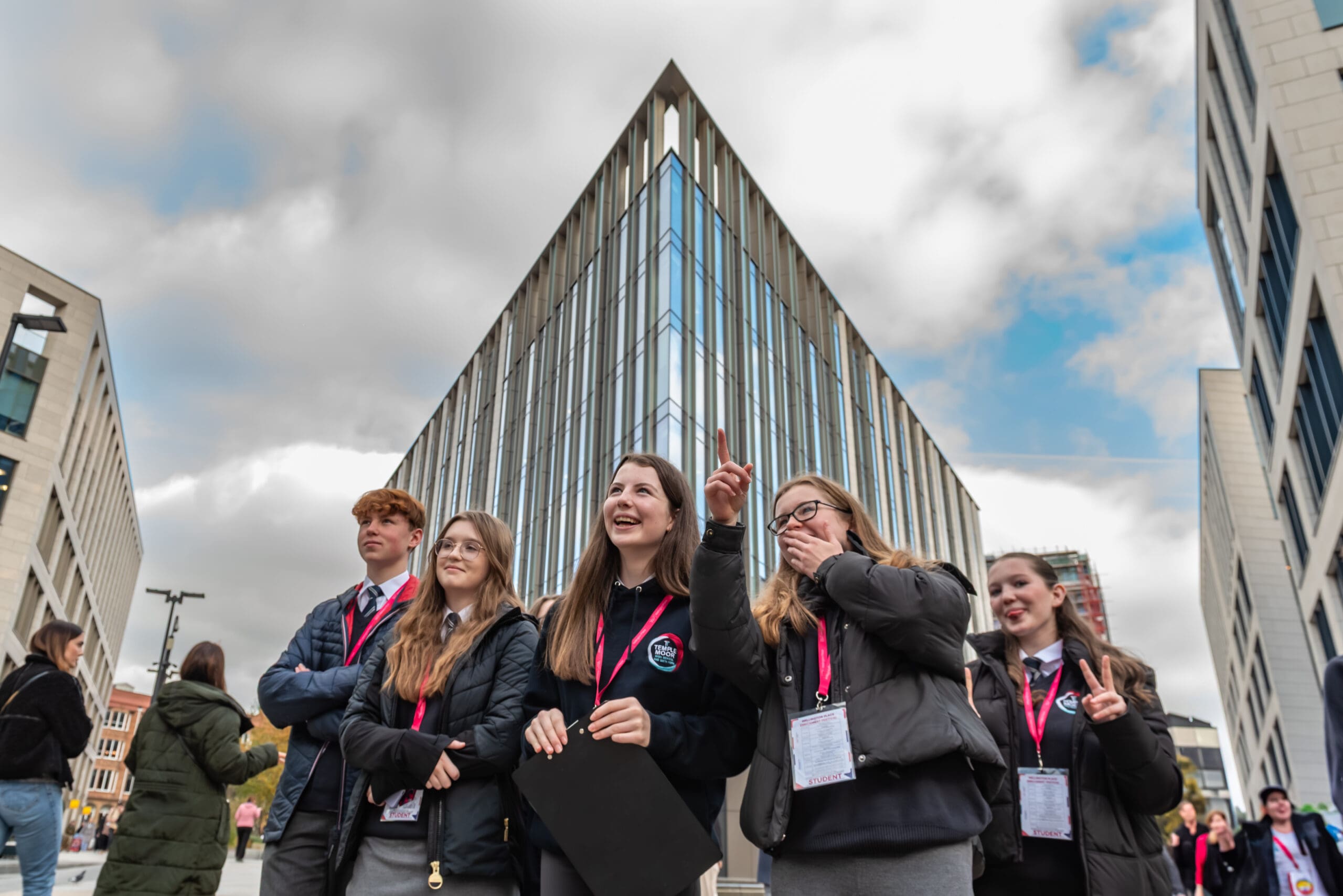 Students looking and pointing with tall building behind them